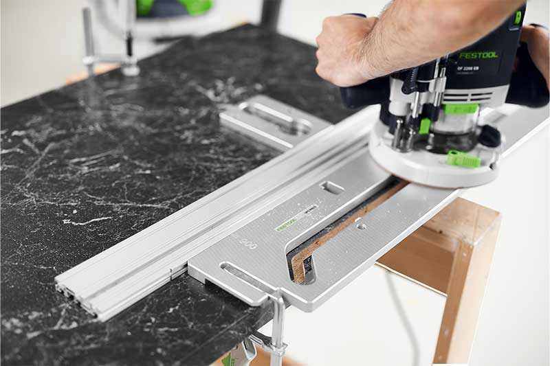 En hantverkare fräser arbetsobjektet med en frässchablon