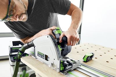 En man med en Festool-såg sågar en bräda på ett multifunktionsbord