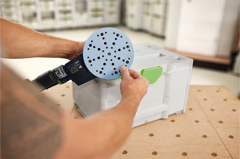 En man fäster ett Granat-slippapper på slipplattan