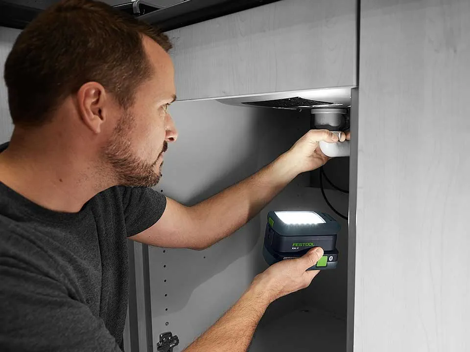 En man belyser anslutningen av ett tvättställ med SYSLITE KAL 2