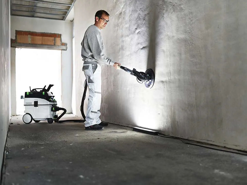 En hantverkare belyser en vägg med hjälp av Släpljus och slipar ner den