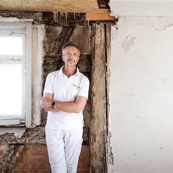 Manfred Schuler, målarmästare och restauratör framför väggen i korsvirkeshuset som ska restaureras