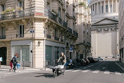 Med sin lådcykel kör ”ébéniste à vélo” snabbt genom de smala gatorna i centrala Paris till en kund, i bakgrunden den berömda kupolen på Panthéon.