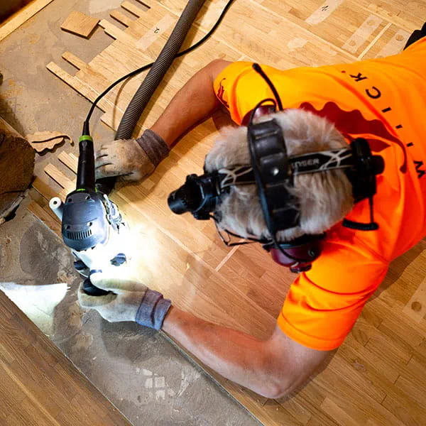 Den finska parkettläggaren bearbetar trägolvet med Festools handöverfräs