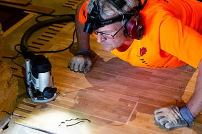 Den finska parkettläggaren bearbetar golvet med Festools handöverfräs