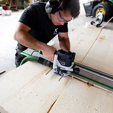 En bastubyggare bearbetar en yta med en handöverfräs från Festool.